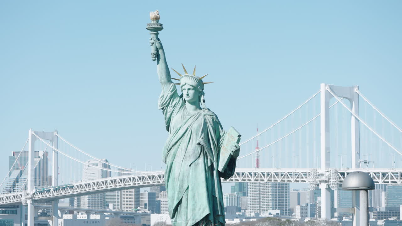 Odaiba Statue Of Liberty Replica Sculpture With View Of Rainbow Bridge And Tokyo Tower In Background At Daytime In Tokyo, Japan