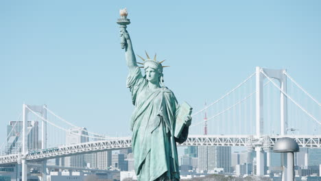 odaiba statue of liberty replica sculpture with view of rainbow bridge and tokyo tower in background at daytime in tokyo, japan