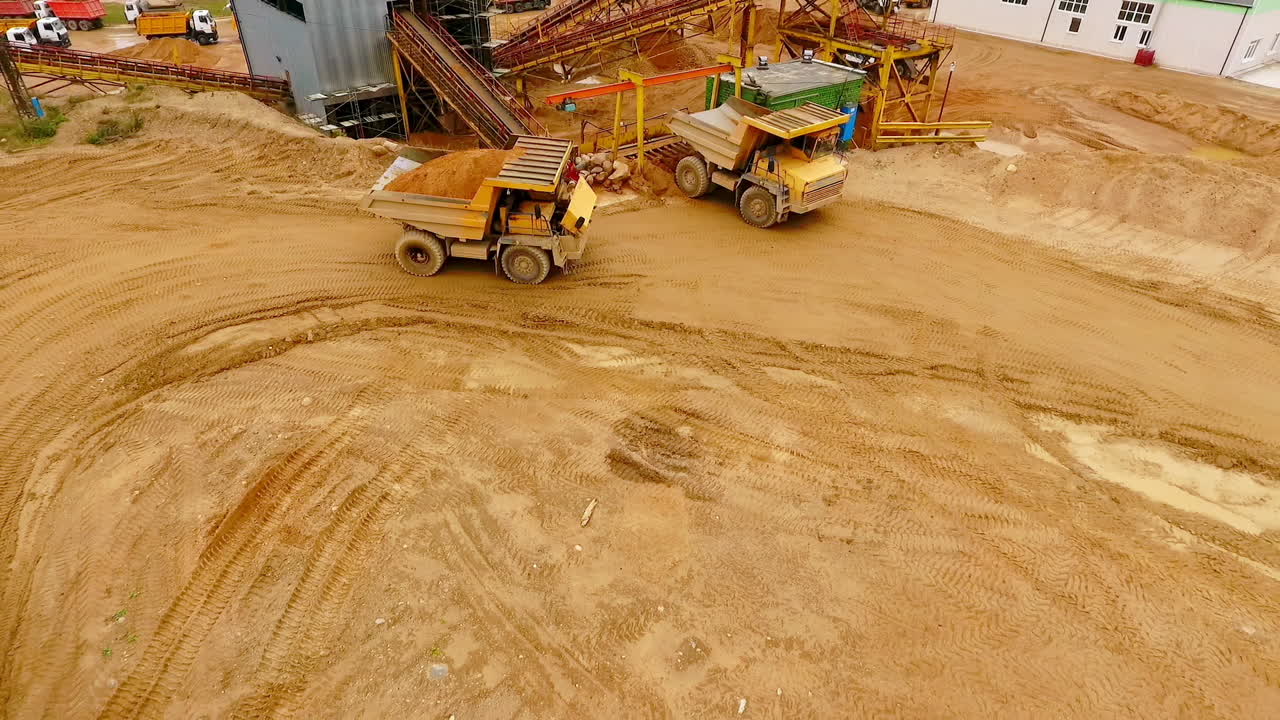 Dumper trucks with sand standing on territory industrial factory. Aerial view