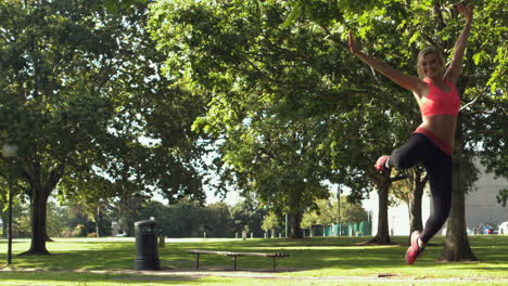 Happy-toned-blonde-jumping-in-the-air-in-park