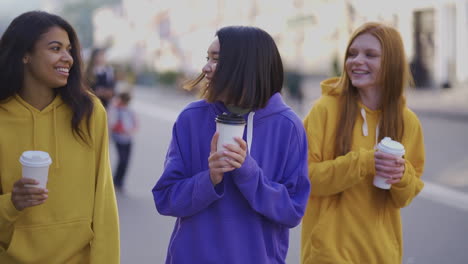 multi ethnic happy women walk together with a takeaway coffee in a recyclable cardboard cup outdoors