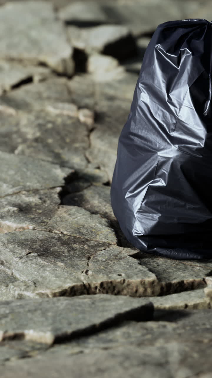 검은색 쓰레기 봉투가 바닥에 앉아 있다.