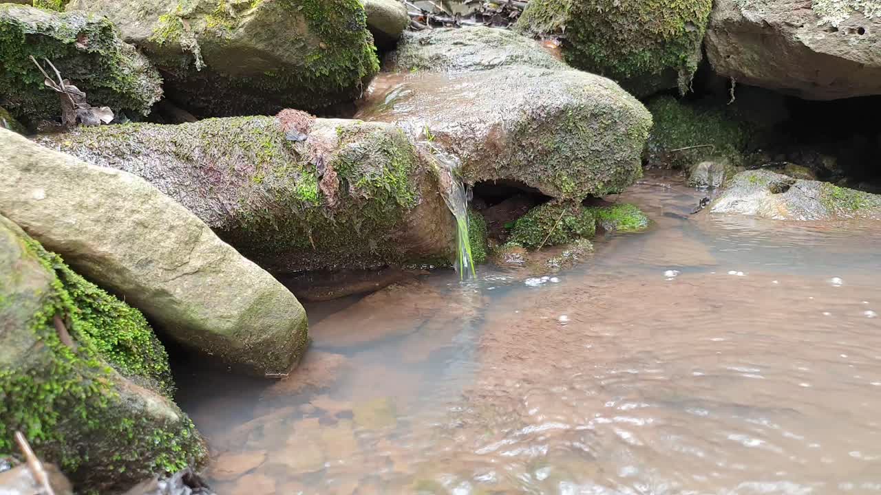 pequeña cascada de un arroyo de manantial de montaña que baja por enormes losas de piedra arenisca con liquen y musgo, agua potable cristalina después de una larga caminata en camelroc