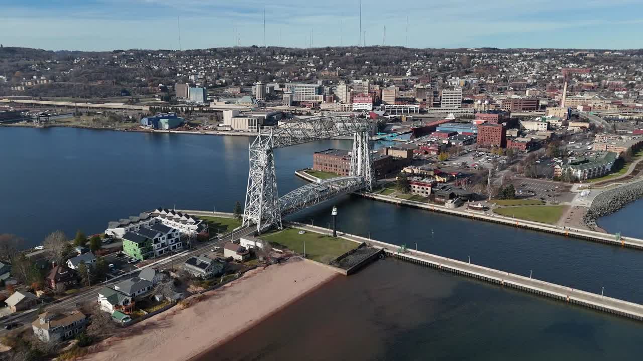 Aerial View, Slowly panning around Aerial Lift Bridge in Duluth Minnesota as cars drive across. businesses, hotels and resorts in background. Late Fall with partly cloudy skies.