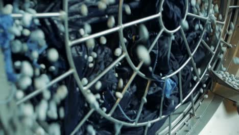 slow motion shot of pumice stones pouring from industrial washing machine into basket in jeans factory