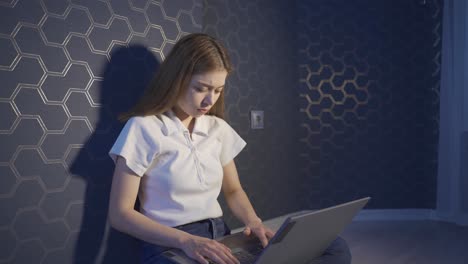 una joven que trabaja con una computadora portátil por la noche está sola.