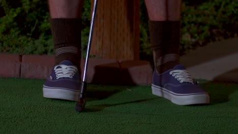 un primer plano de una mini pelota de golf morada siendo golpeada con un palo