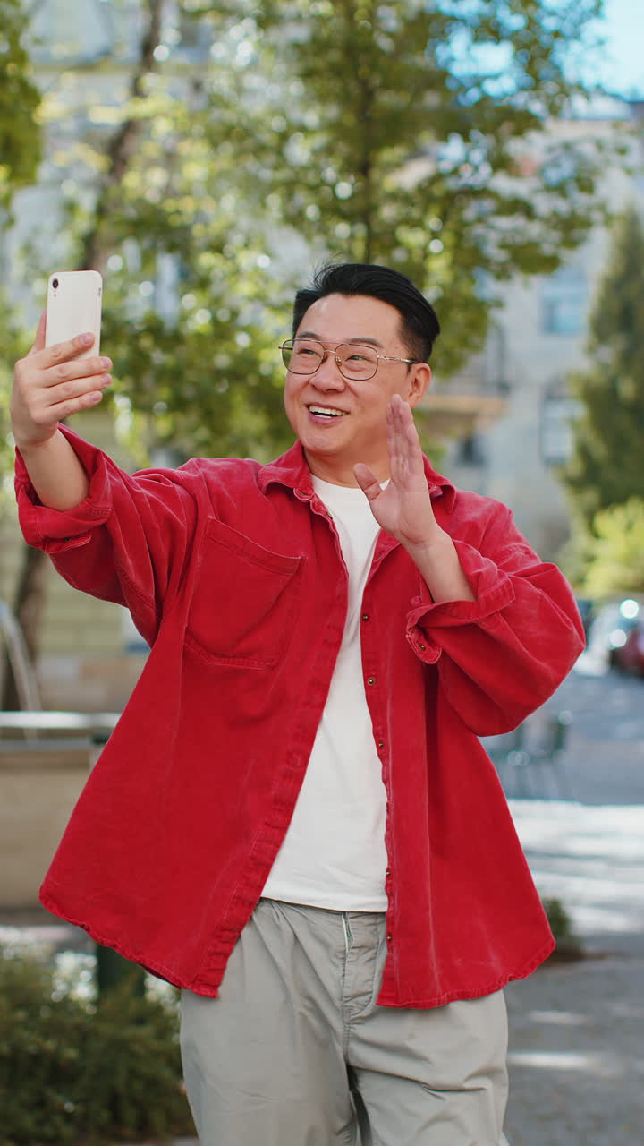 Un blogger asiatico che si fa un selfie su uno smartphone e fa una videoconferenza online con gli abbonati in una strada della città