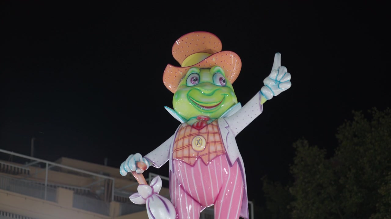 Estatua iluminada de una rana mascota por la noche