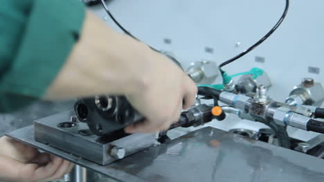 Worker twisting industrial unit to metal basis. Manual assembly at factory