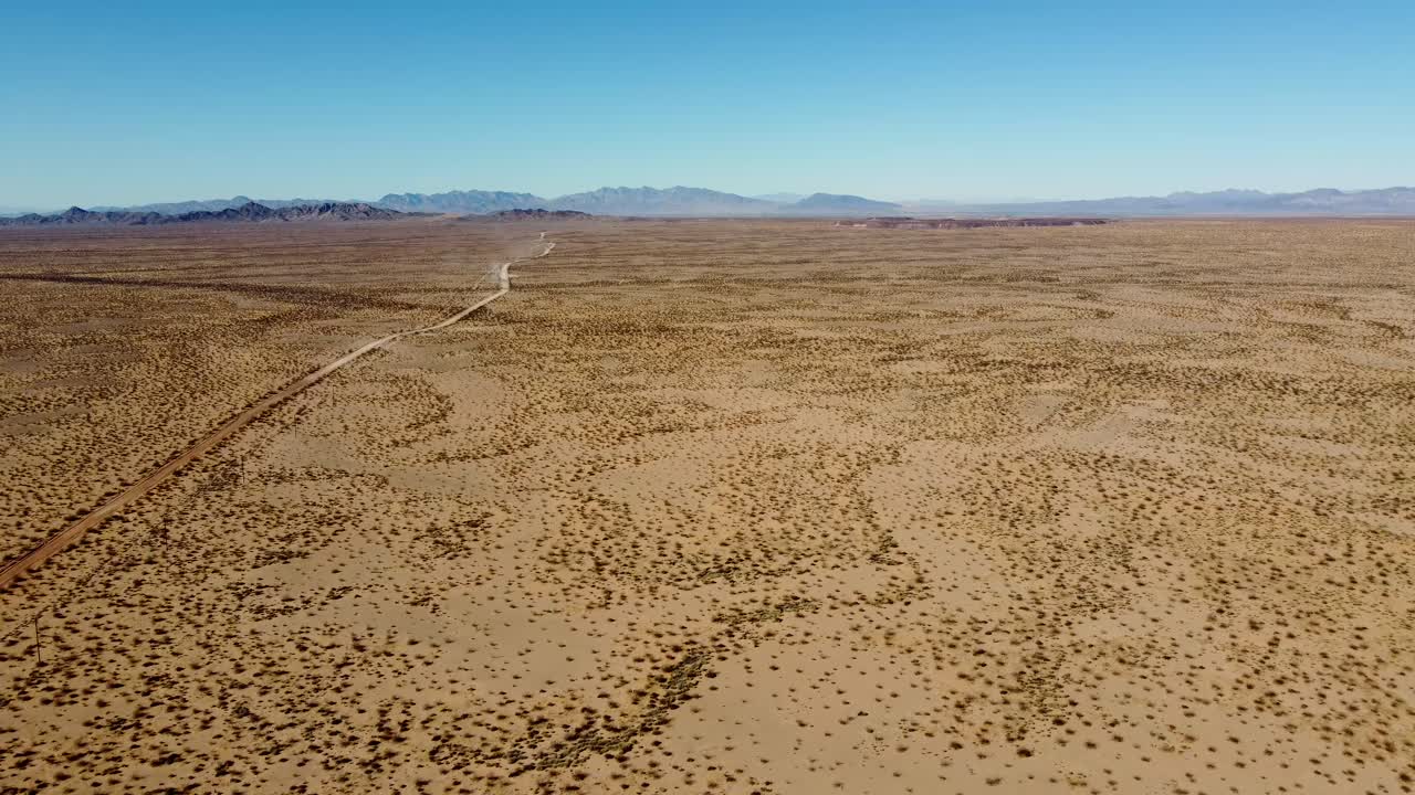 US, AZ, Quartzsite, Copperstone Mine, 2025-01-14 - Drone view flying over open desert with a road on the left and the giant Copperstone Mine tailings pile in the far distance