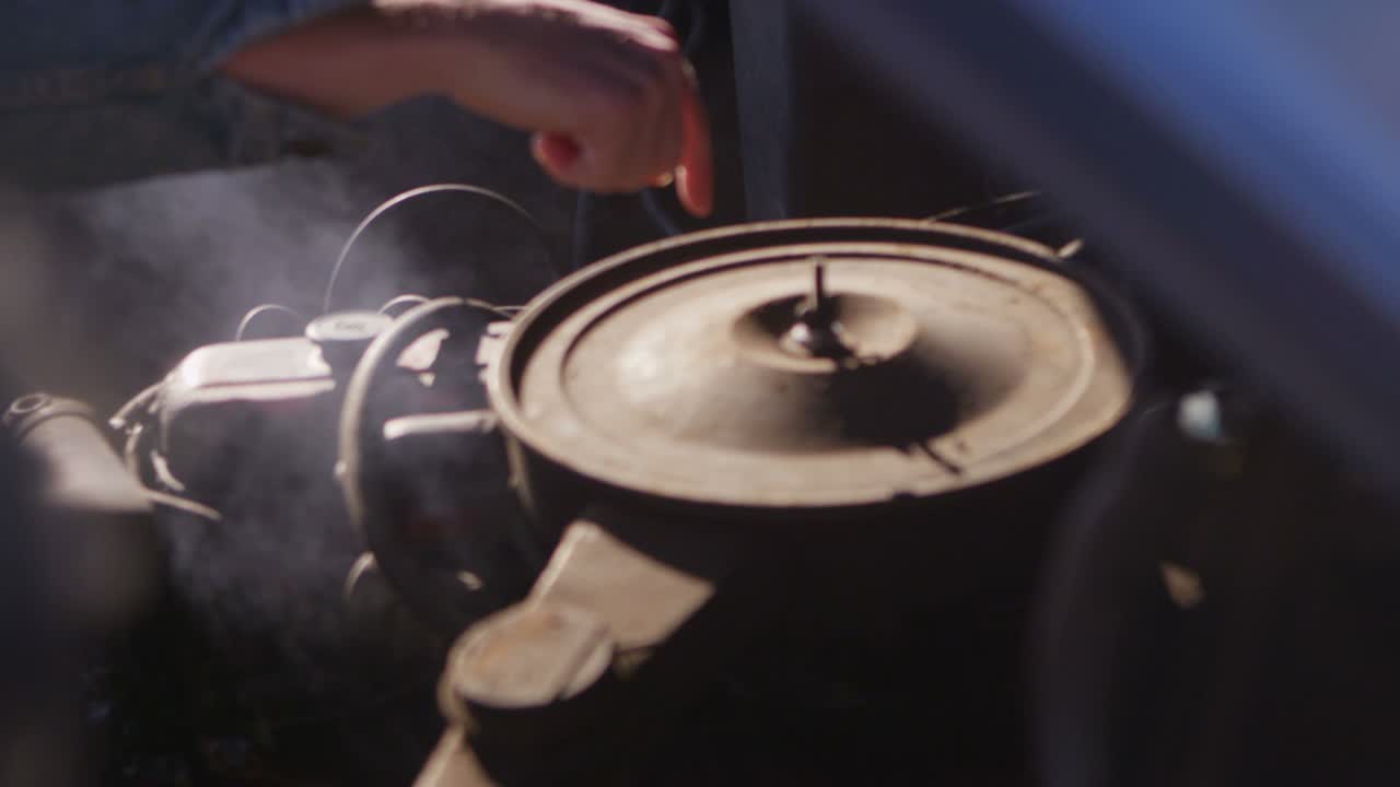 오래된 시보레 픽업트럭 엔진이 김이 나고 손가락이 문제 부품을 가리킬 때 클로즈업