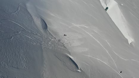 4k drone footage of snowboarder on steep slope with sluffing snow