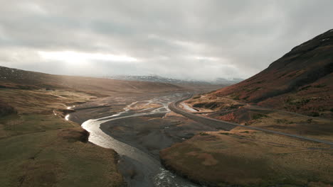 aerial parallax over gorgeous iceland river valley, sunbeams shining through clouds