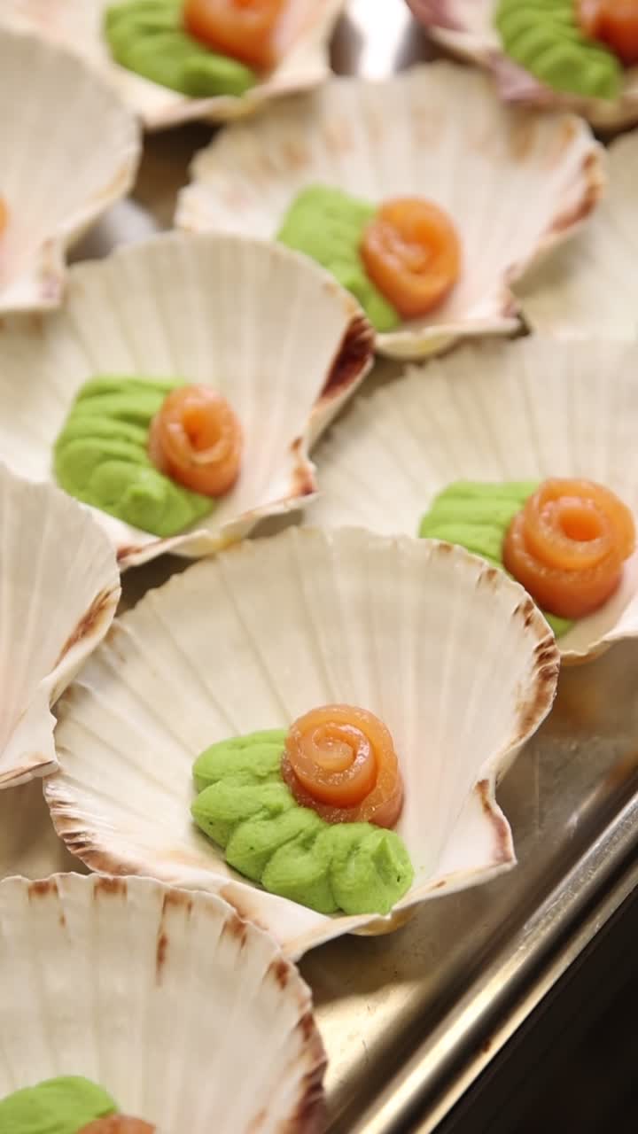 Amuse-bouches gastronomiques au saumon et à la purée verte dans des coquilles Saint-Jacques