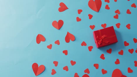 multiple red paper hearts and red present at valentine's day on blue background