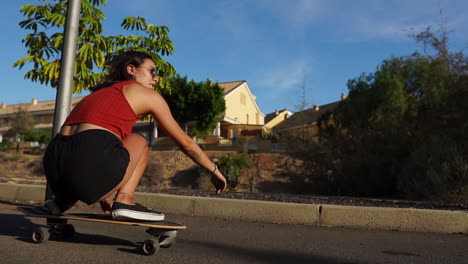 Summer's-essence-unfolds-as-a-young-woman-rides-a-longboard-near-palm-trees-in-slow-motion,-attired-in-shorts-and-sneakers