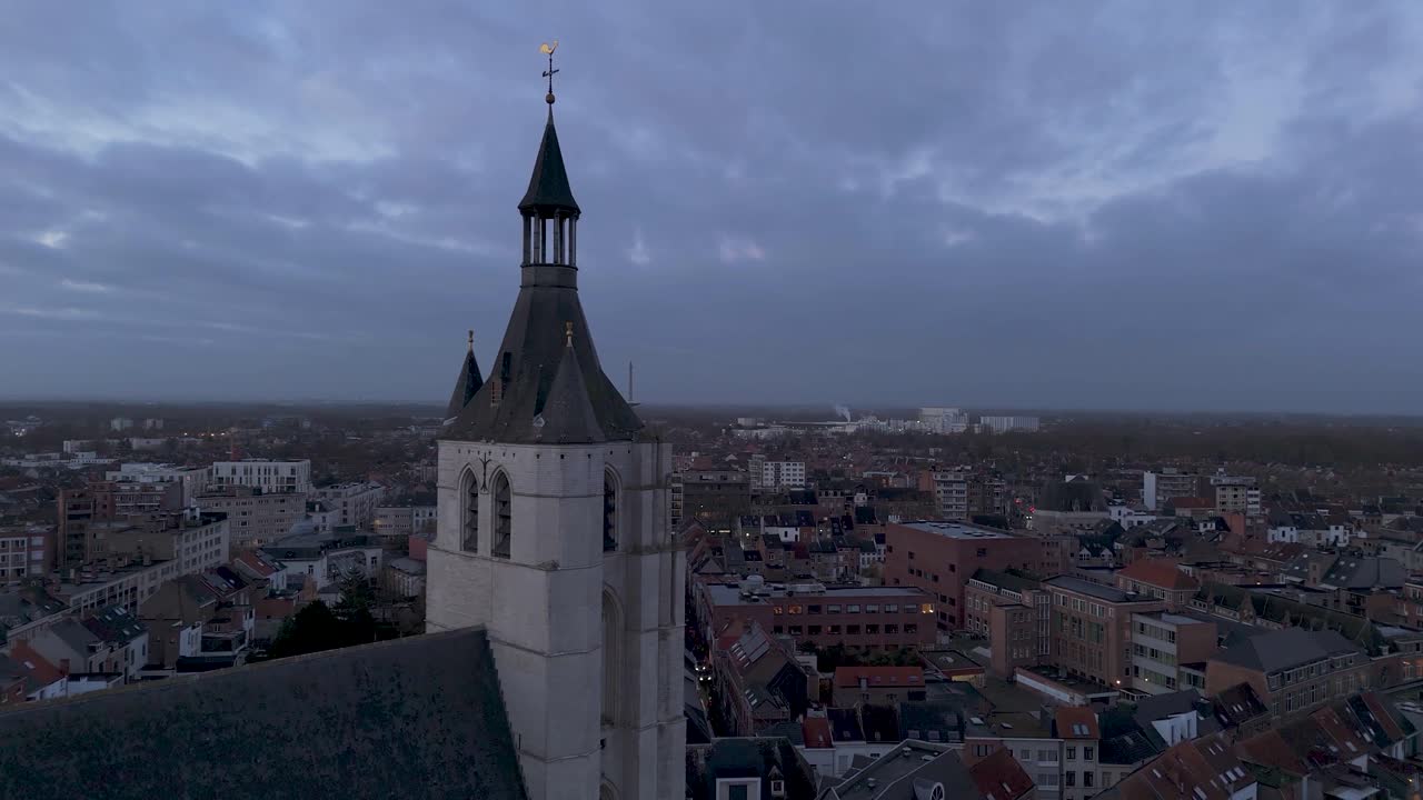 Drone shot of a church in a city center on a cloudy day just before sunset.
