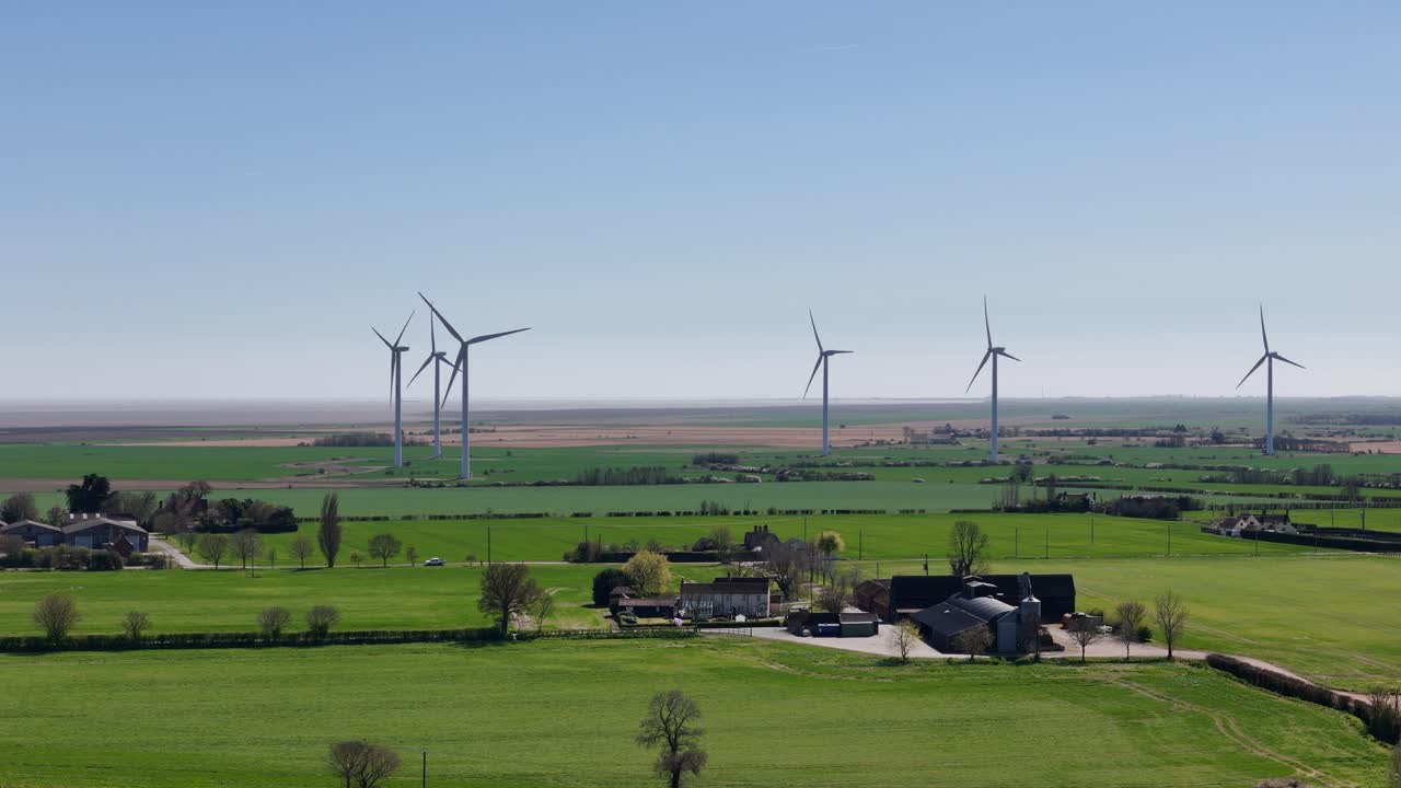 Wind farm turbines in Bradwell Essex UK Panning drone aerial clear blue sky