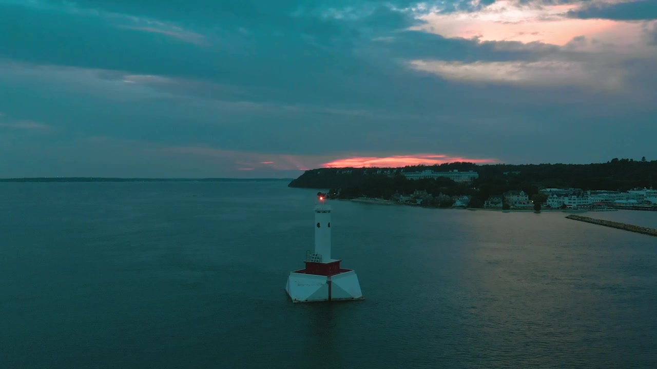 Vista aerea di faro che lampeggia al tramonto su lago calmo