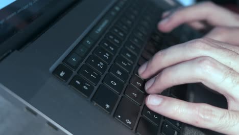 close-up of man's hands swiftly typing on laptop keyboard