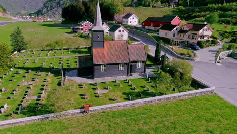 aerial orbit shot of norwegian church surrounded by graveyards during sunny day