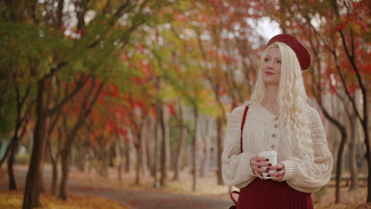 Donna lituana che si gode un drink mentre passeggia nel Parco Forestale di Yangjae, con vivaci colori autunnali tutt'intorno, spazio per il testo.