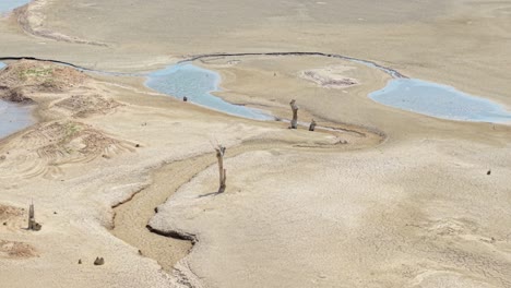 aerial of curved dry terrain next to low reservoir shoreline in rural greece area