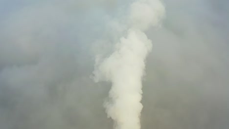 smoke from a power station chimney rising from a low, creeping fog. drone view