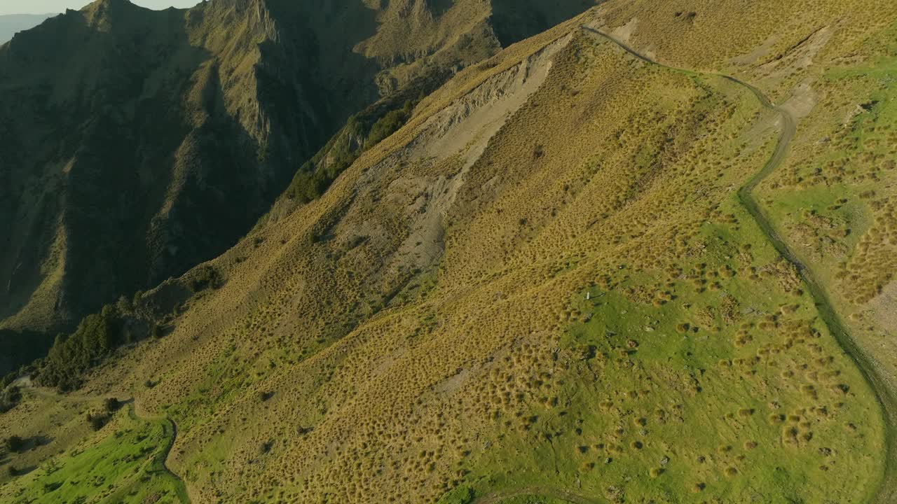 Sentiero di montagna sull'Isthmus Peak che sale su un ripido pendio in Nuova Zelanda, all'alba.