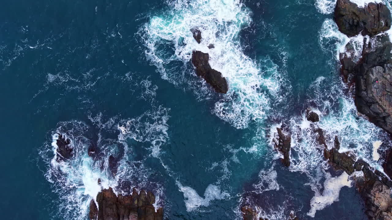 Le onde si infrangono sulle scogliere frastagliate sotto un cielo blu intenso, mostrando la bellezza della natura sulla costa
