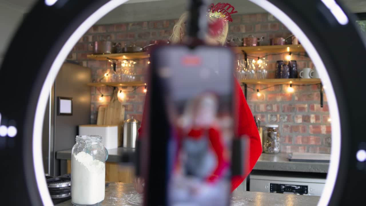 Smartphone recording female cook kitchen showing dough sprinkling flour rolling for Christmas bake