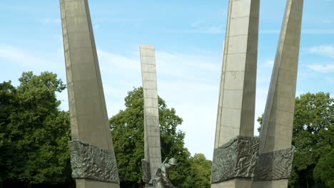 Statue-of-a-soldier-at-Pomnik-Chwała-Saperom,-Warsaw,-with-relief-pillars--