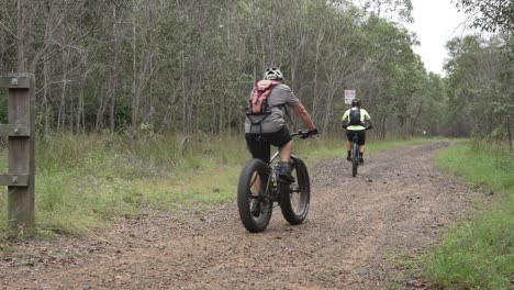 Group-of-cyclists-pass-by-camera-and-cycle-down-dirt-road