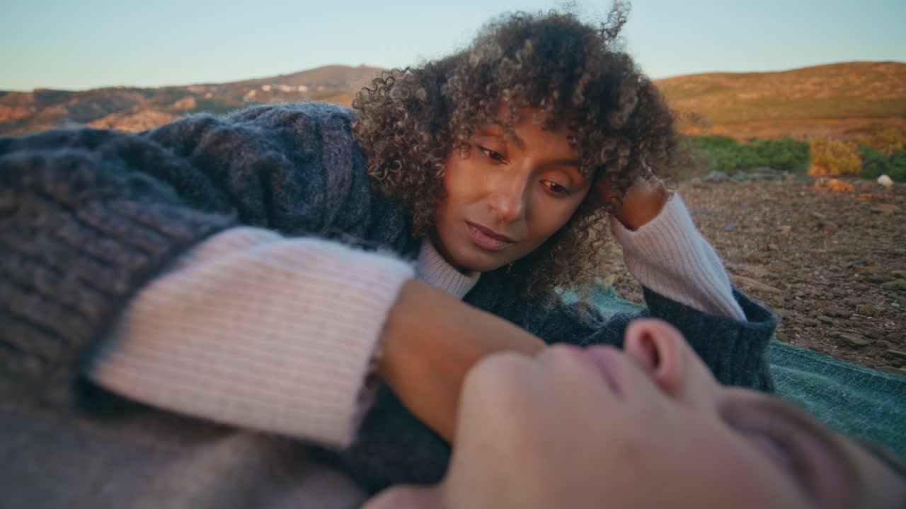 Lying pair dating sunset hill picnic closeup. Woman stroking boyfriend cheek