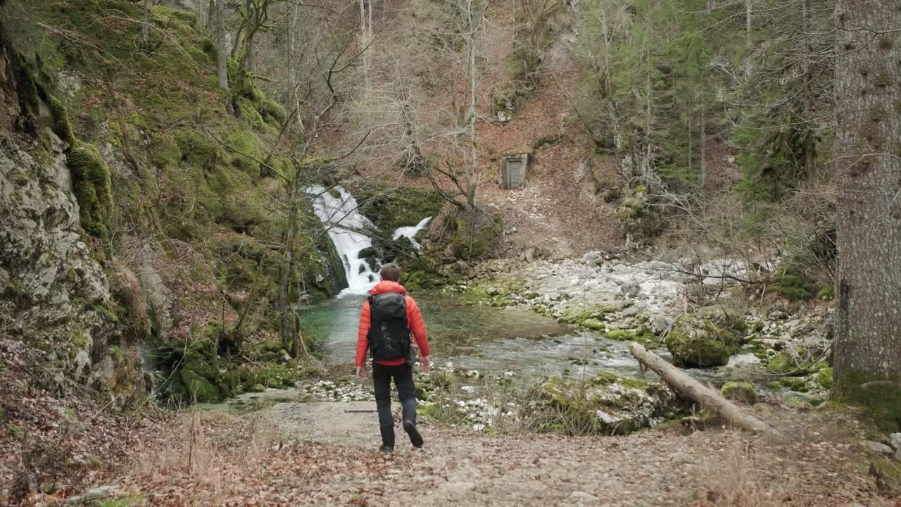hombre caminando hacia el río y la cascada