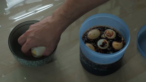 placing hard-boiled eggs in a container full of soy sauce marinade and storing away. -static shot