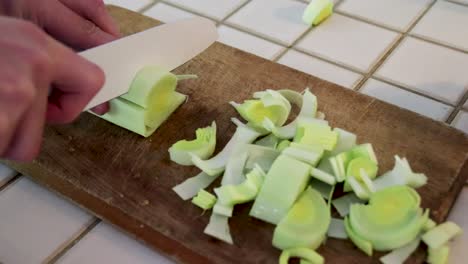 cutting a leek on wooden board in kitchen, vegetable, 356% speed