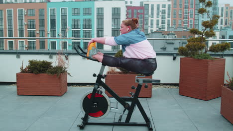 caucasian woman coach making stretching aerobic training exercises on stationary bike outdoors