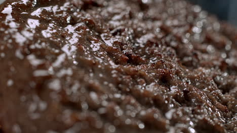 grilling a beef burger on the grate - the juicy meat sizzles from the hot fire in macro