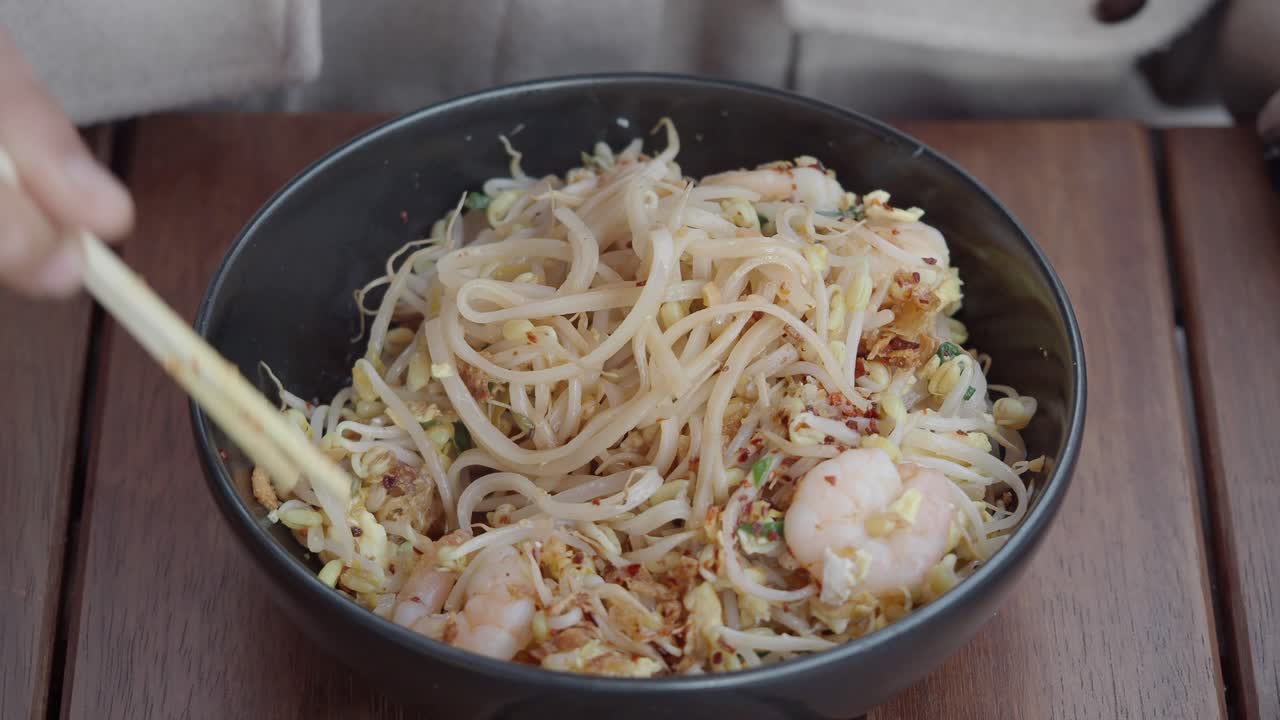 Close-up Tangan Memakan Mi Pad Thai dengan Udang dan Tauge