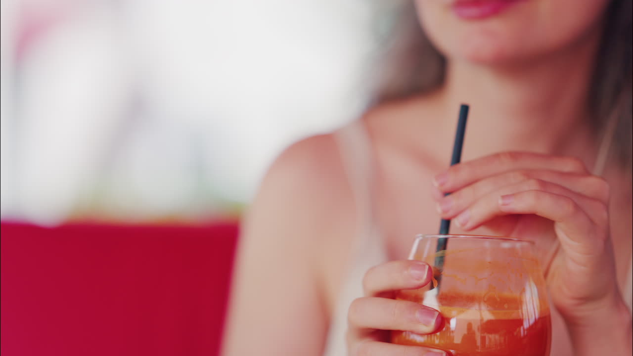 Close up of a woman sipping fresh carrot juice through a straw