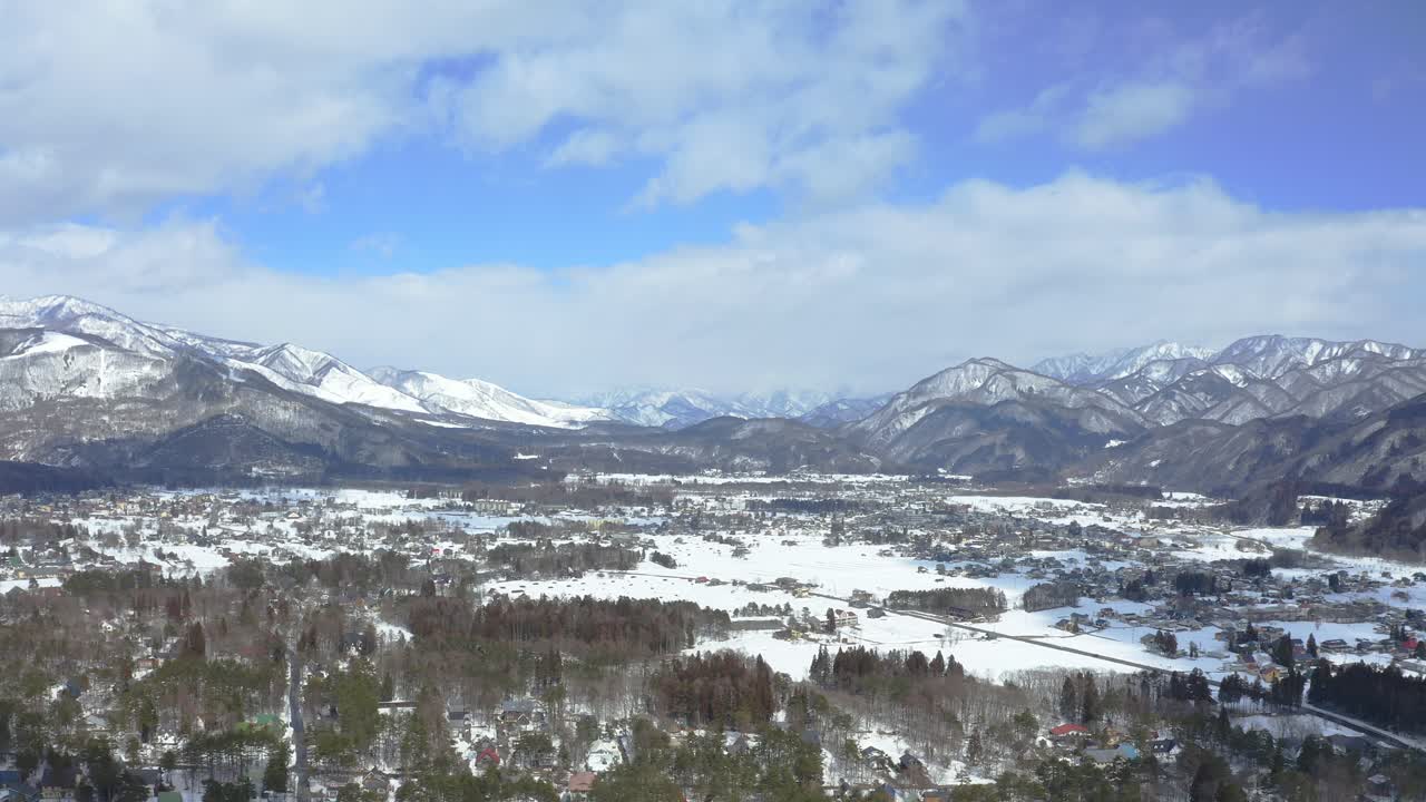 Through aerial cinematography, a vivid portrait of Hakuba valley and it's city in Japan during winter, showcasing the breathtaking combination of snow-capped scenery, lush forests, and urban life
