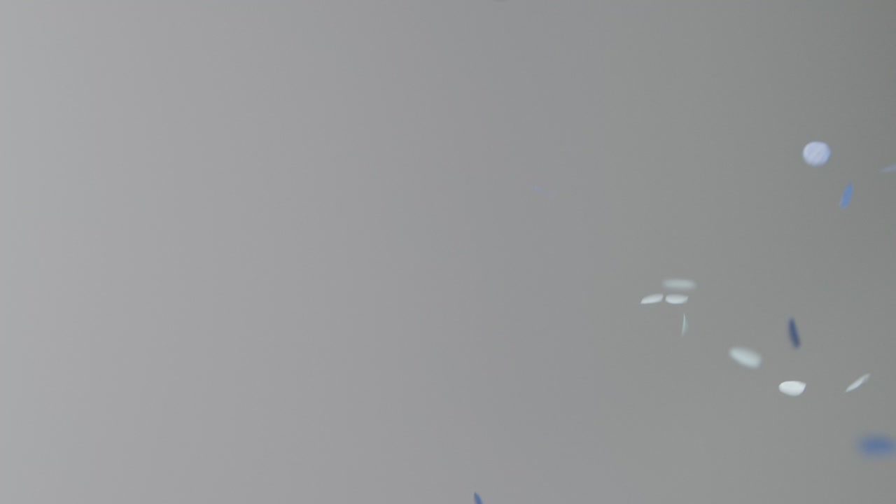 회색 배경에 떨어지는 파란색과 금색 색종이의 고정 샷