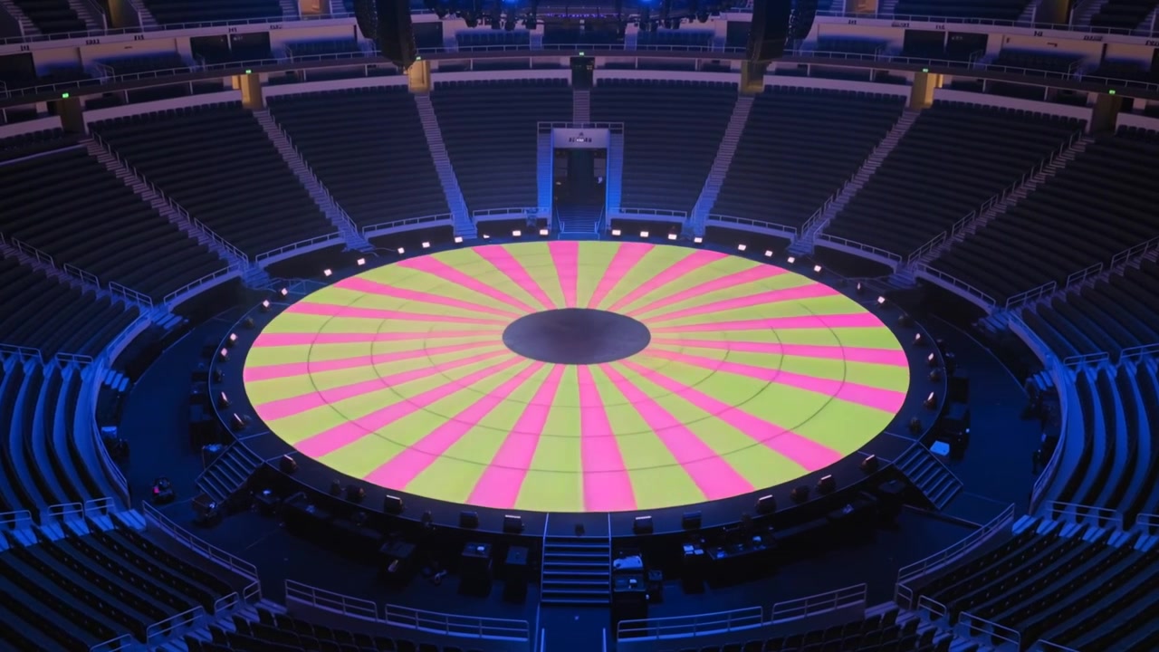 La squadra luci che invia segnali, illuminando un pavimento LED rotondo e fasci di luce spot nell'arena per un test pre-spettacolo.