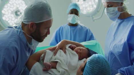 Side-view-of-Caucasian-couple-with-surgeons-holding-their-newborn-baby-in-operation-theater-4k