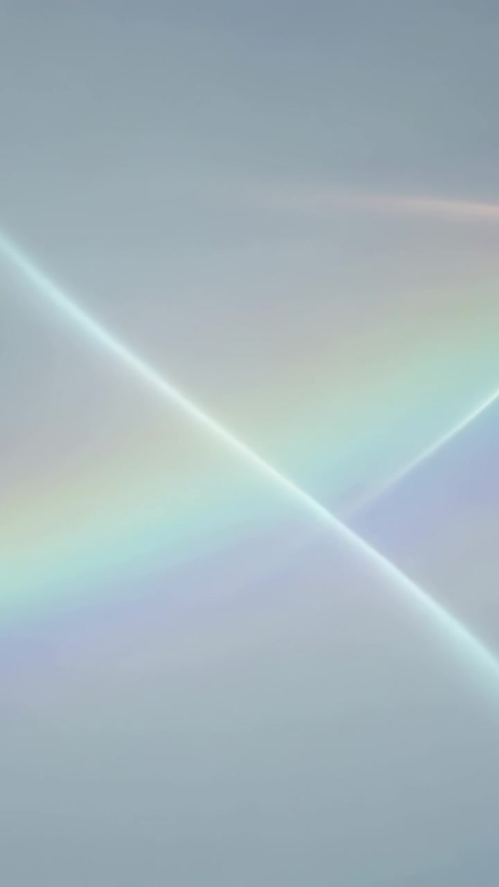 Vertical video: Radiating rainbow band brightening blue sky from sunlight, forming crossing streaks
