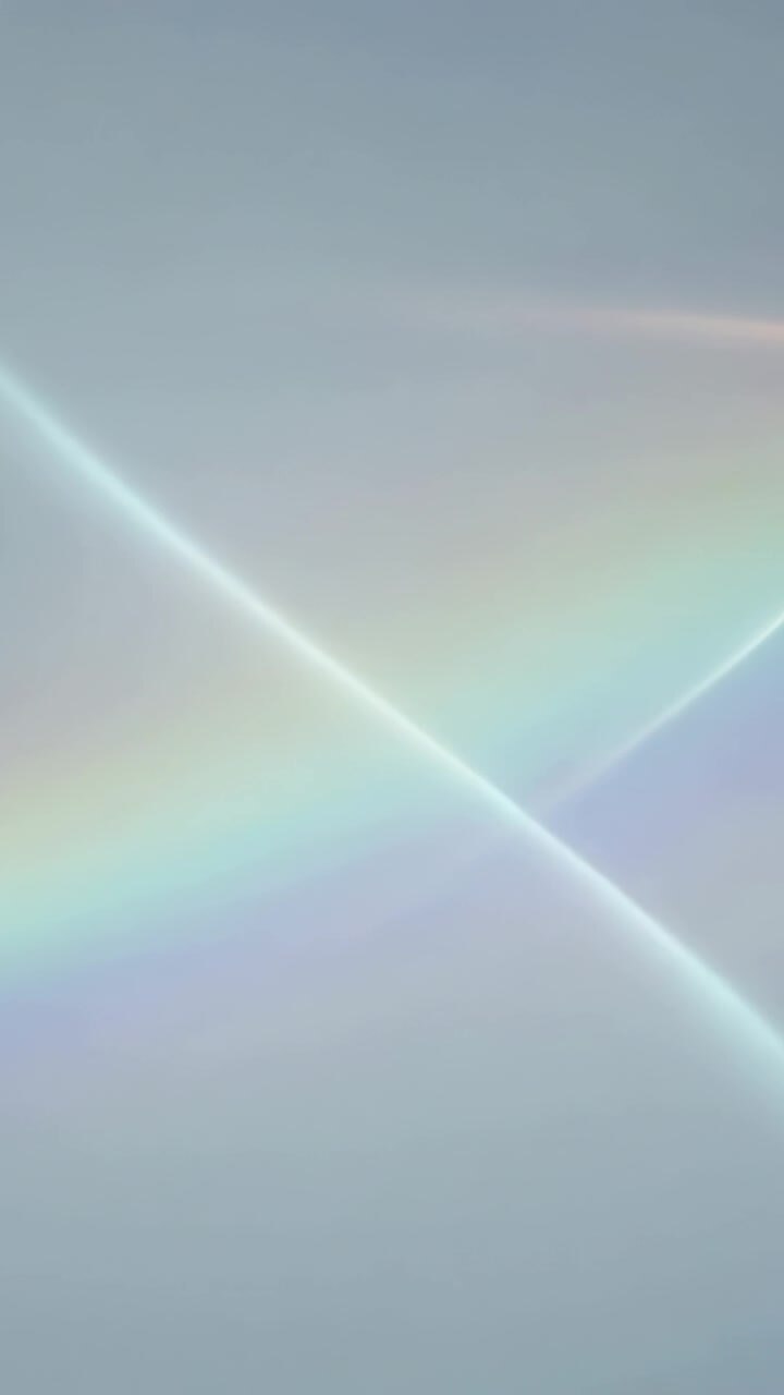 Video verticale: Fascia arcobaleno radiosa che illumina il cielo blu dalla luce del sole, formando strisce incrociate.