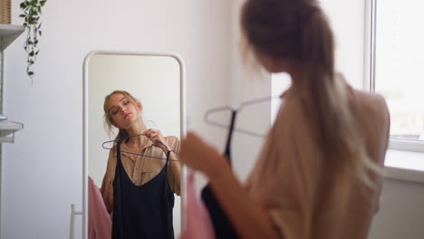 woman looks at reflection in mirror choosing dress for party