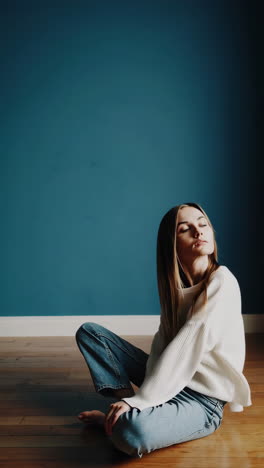 woman relaxing in natural light by a blue wall
